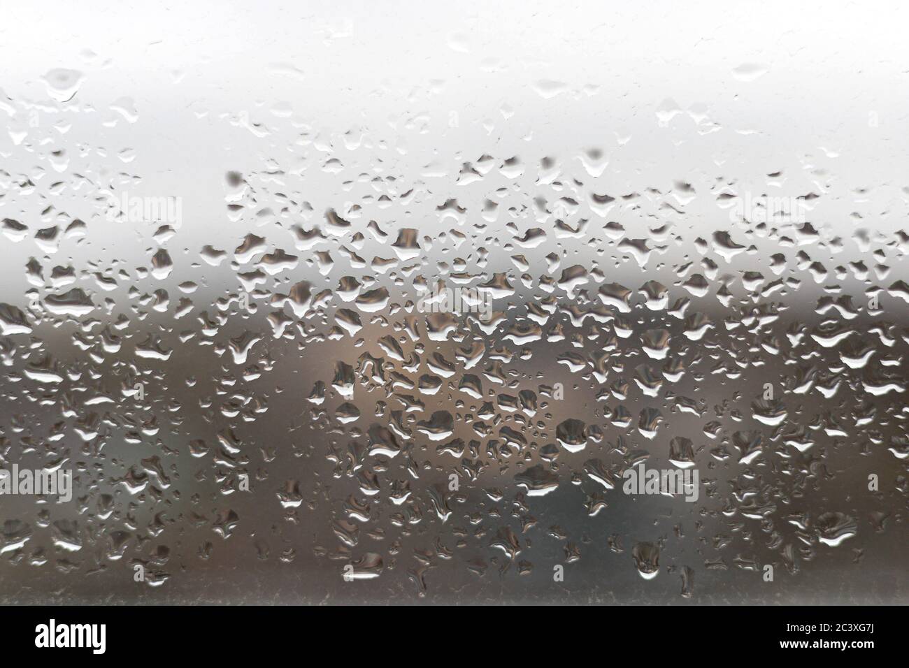 Gros plan des gouttes d'eau sur la vitre. La pluie tombe sur le verre. Arrière-plan, fond d'écran, texture flou Banque D'Images