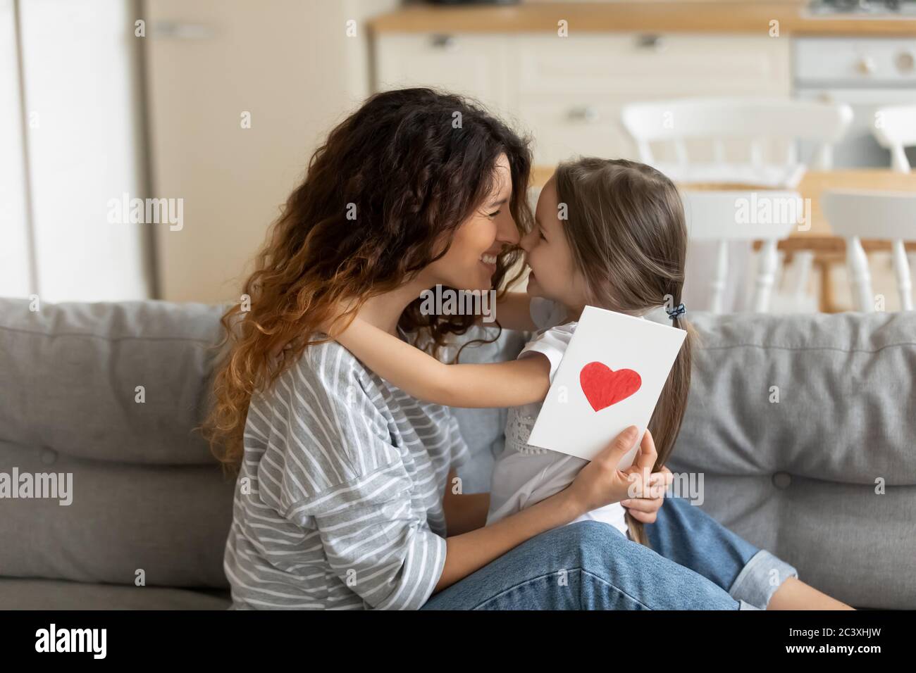 Gros plan jeune mère tenant une carte postale cadeau avec coeur. Banque D'Images