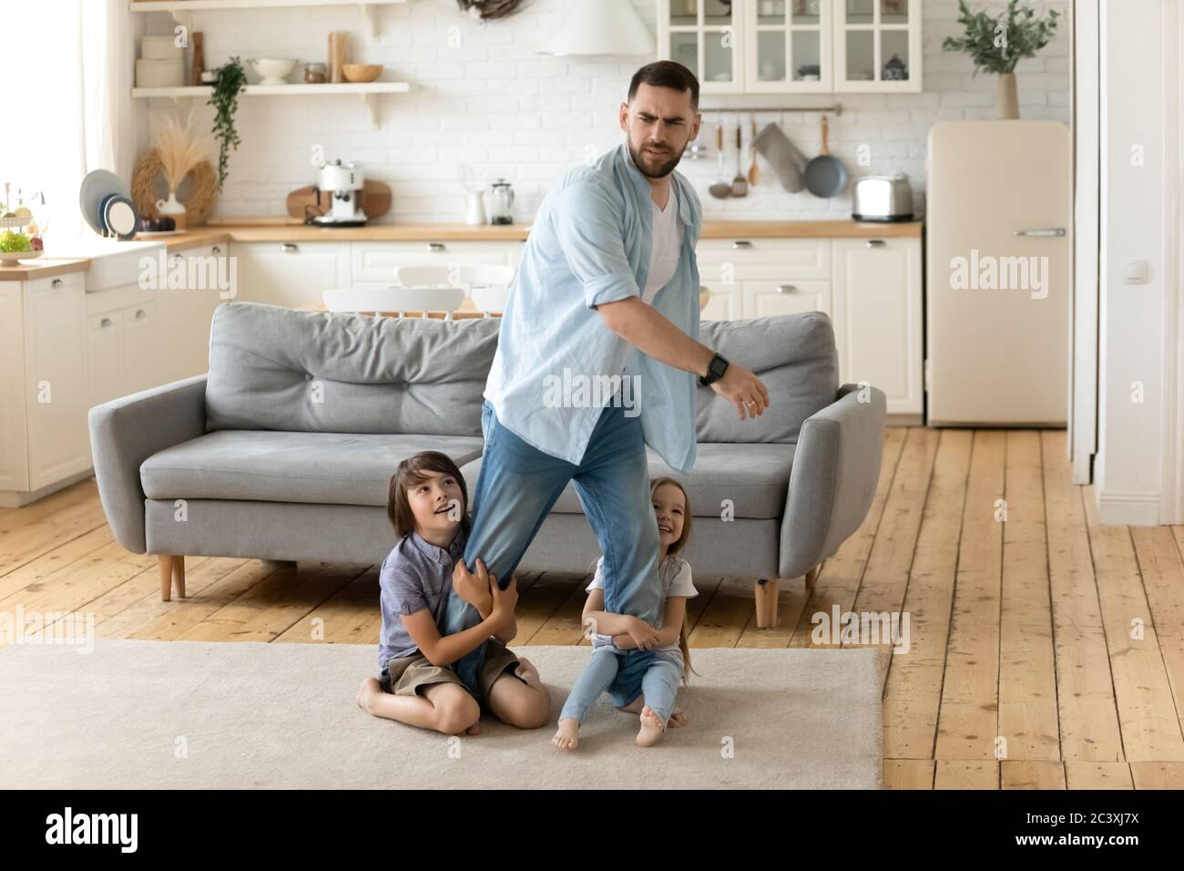 Enfants hyperactifs tenant des jambes de père fatiguées. Banque D'Images