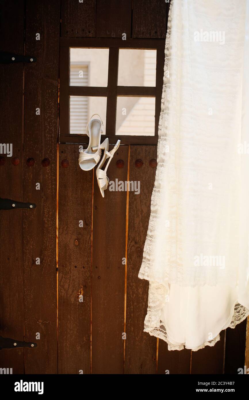 Une paire de chaussures et une robe de mariage accrochée à une porte de style espagnol. Banque D'Images