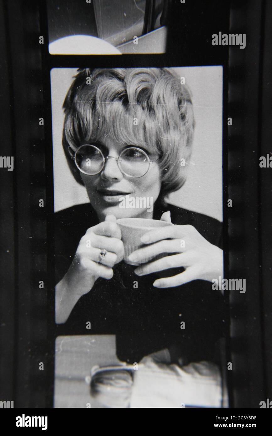 Fin 70s vintage contact imprimé photo noir et blanc d'une femme dans un coiffo bouffant sirotant une tasse de café. Banque D'Images
