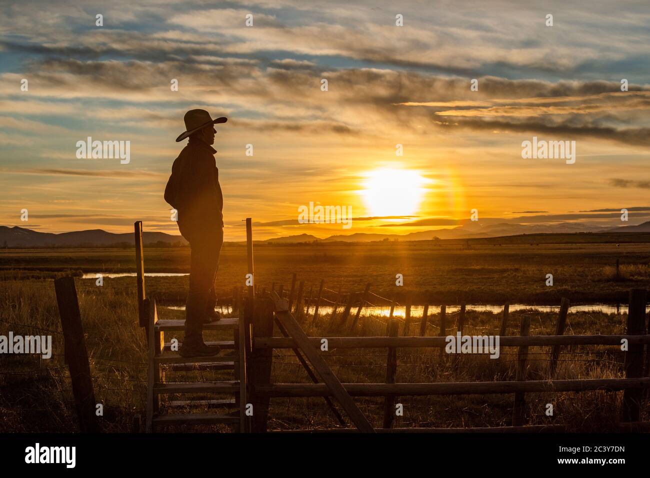 États-Unis, Idaho, Bellevue, Cowboy debout sur la clôture au coucher du soleil Banque D'Images