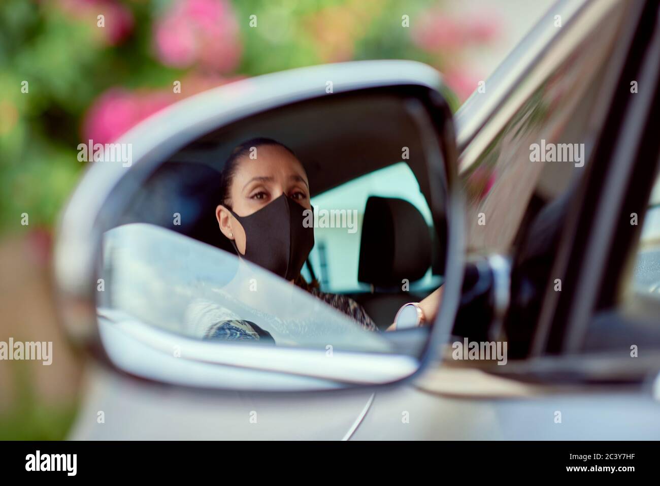 Femme avec masque de conduite voiture réfléchie dans le miroir Banque D'Images
