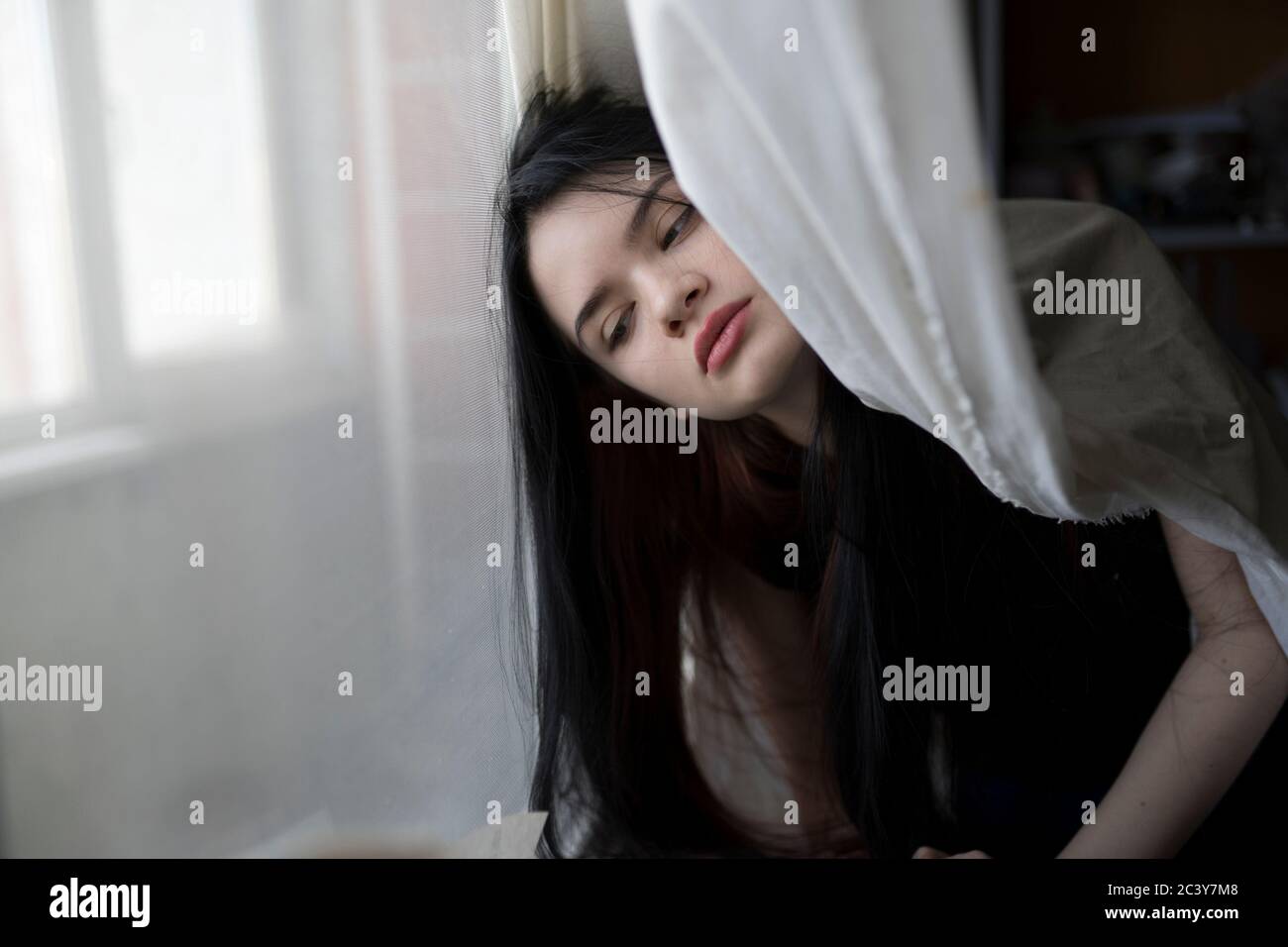 Jeune femme penchée par la fenêtre Banque D'Images