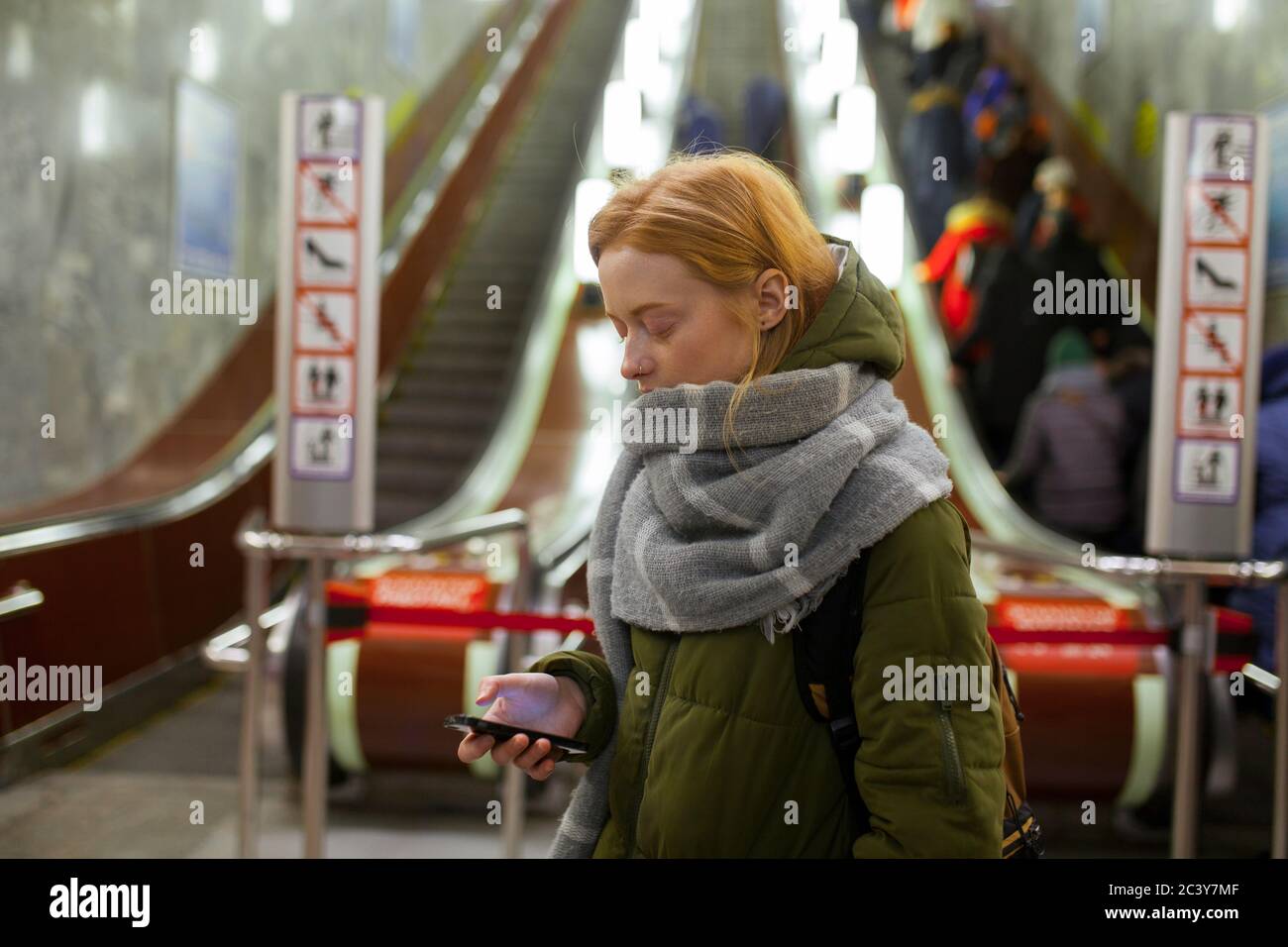 Russie, Novosibirsk, jeune femme avec smartphone debout près de l'escalator Banque D'Images