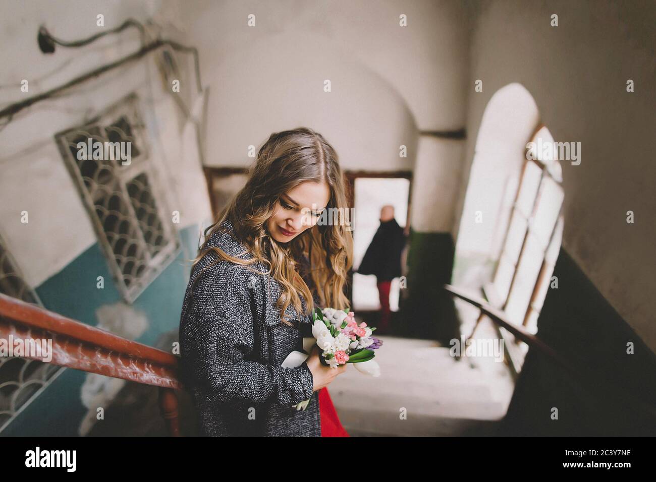 Mariée debout sur les escaliers pendant que le marié attend à l'entrée Banque D'Images