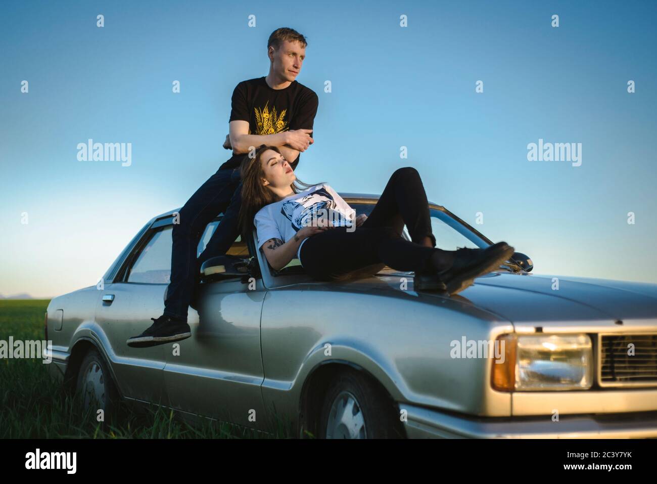 Ukraine, Crimée, couple assis sur une vieille voiture dans un paysage rural Banque D'Images