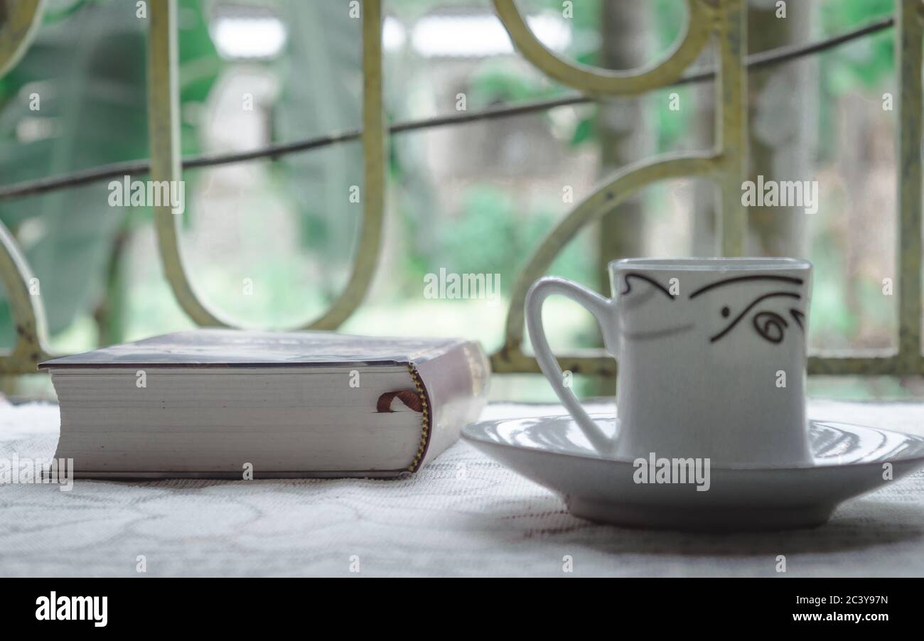 Une tasse de café et un livre sur la lumière du soleil fenêtre le matin. Il est temps de terminer un roman pour découvrir quelque chose de nouveau pendant la période de distanciation sociale. Restez à la maison Banque D'Images