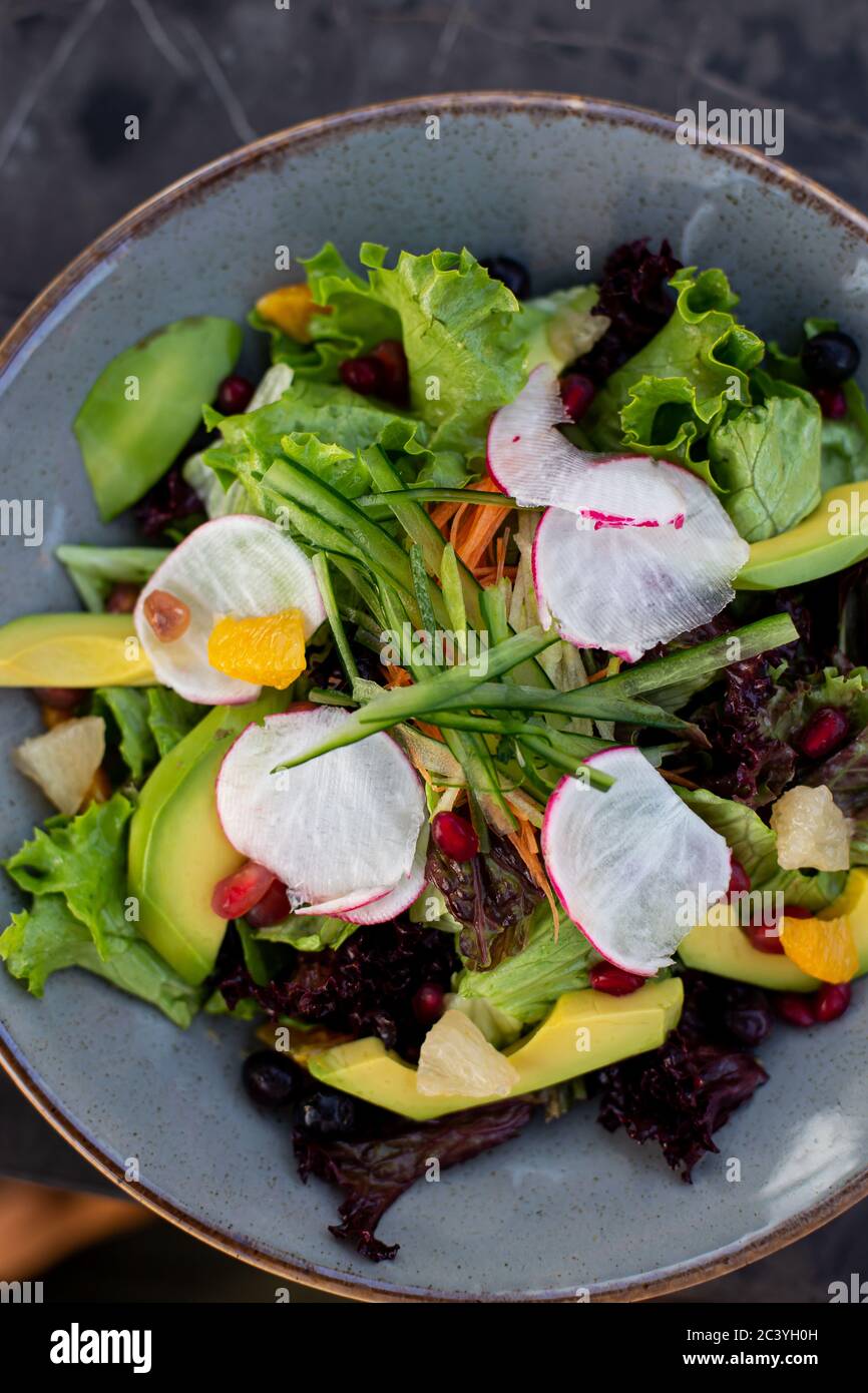 Image TopView de salade de légumes avec navets, légumes verts, avocat, concombre dans un bol en céramique bleu foncé. Banque D'Images