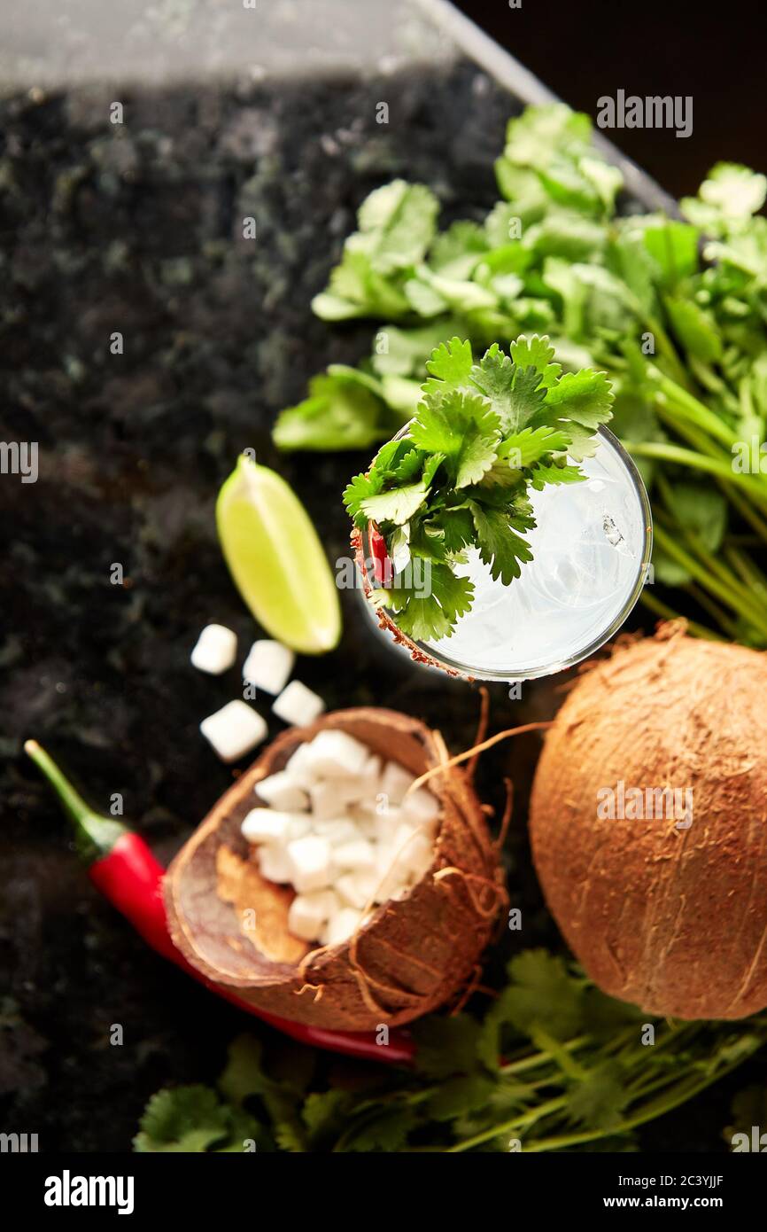 Cocktail au rhum, au sirop de coco, à la coriandre, au citron vert et au piment rouge sur le comptoir en marbre noir Banque D'Images