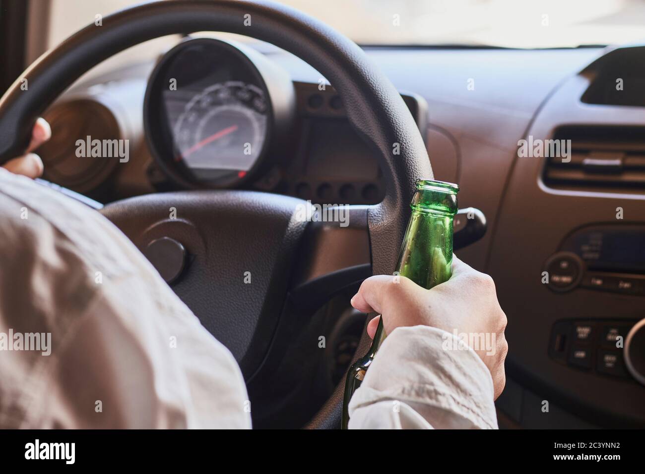 Une femme méconnue boit de la bière en voiture. Concepts de conduite sous influence, conduite en état d'ivresse ou conduite avec facultés affaiblies Banque D'Images