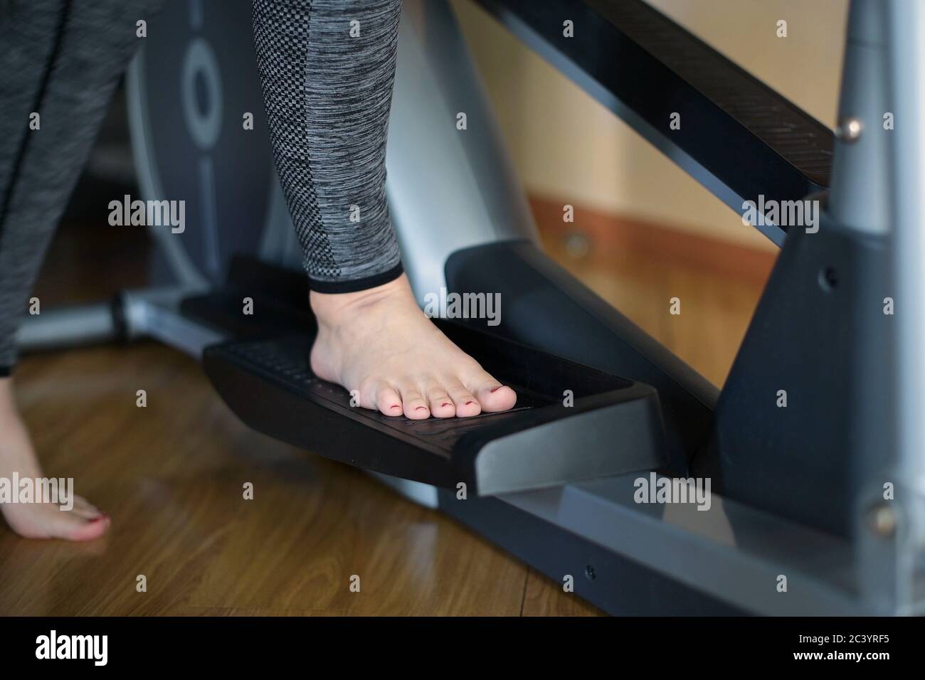 Une fille pieds nus se tient sur la pédale d'un ellipsoïde et commence la formation Banque D'Images