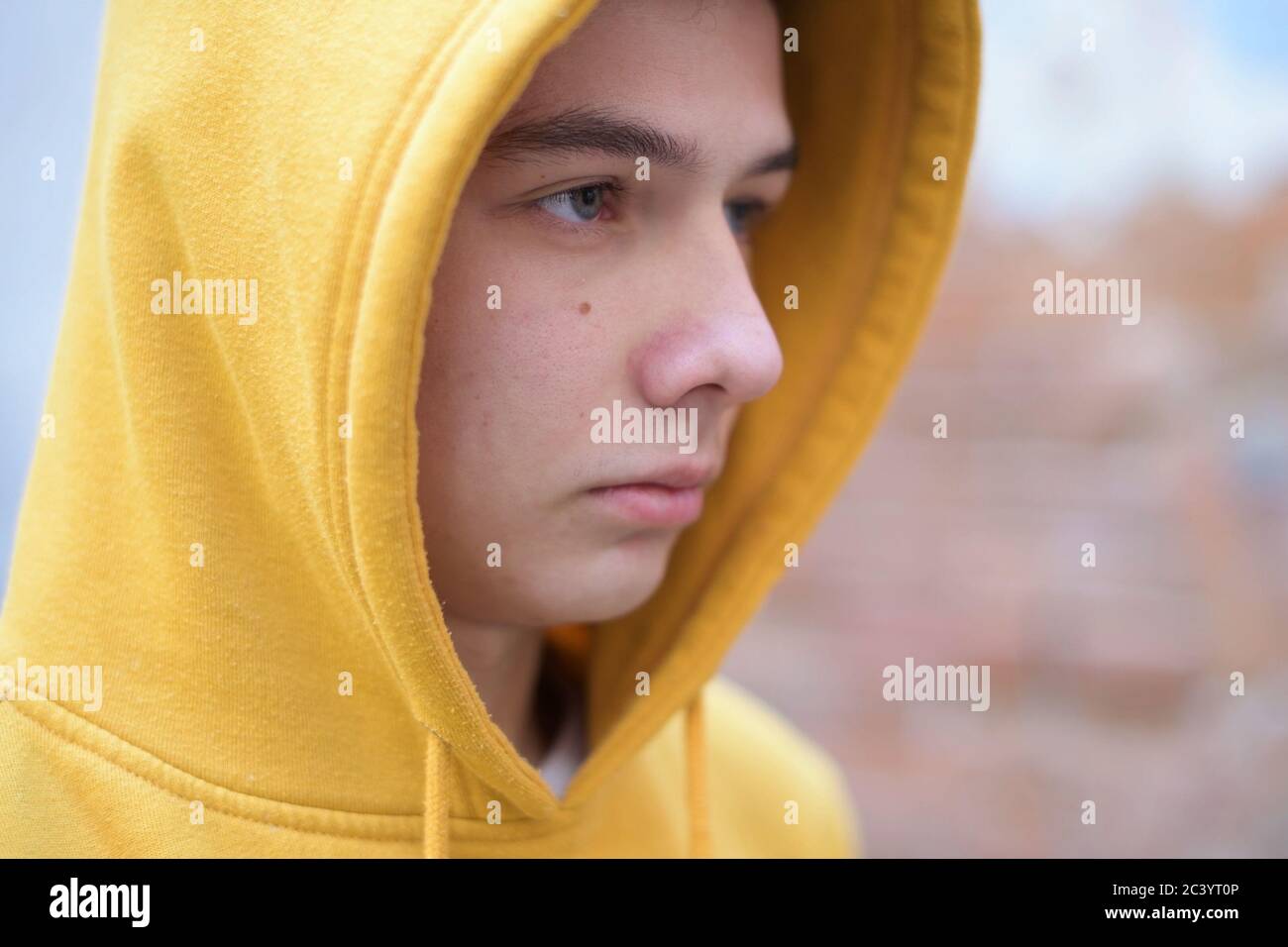 un adolescent dans un sweat-shirt jaune regarde devant lui Banque D'Images