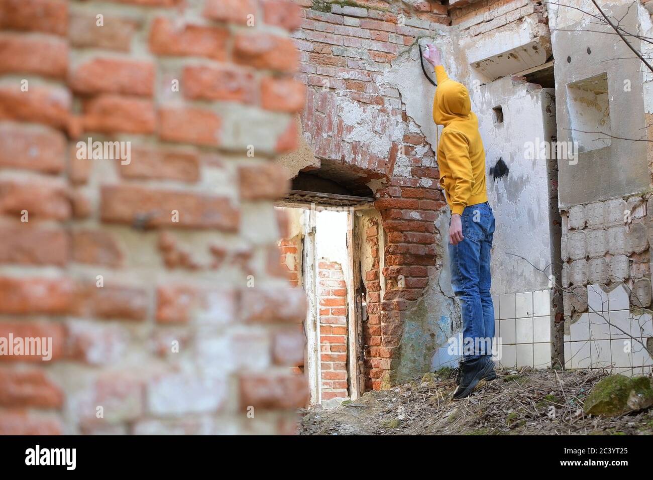 Un jeune homme dessine de la peinture en aérosol sur le mur d'un bâtiment abandonné Banque D'Images