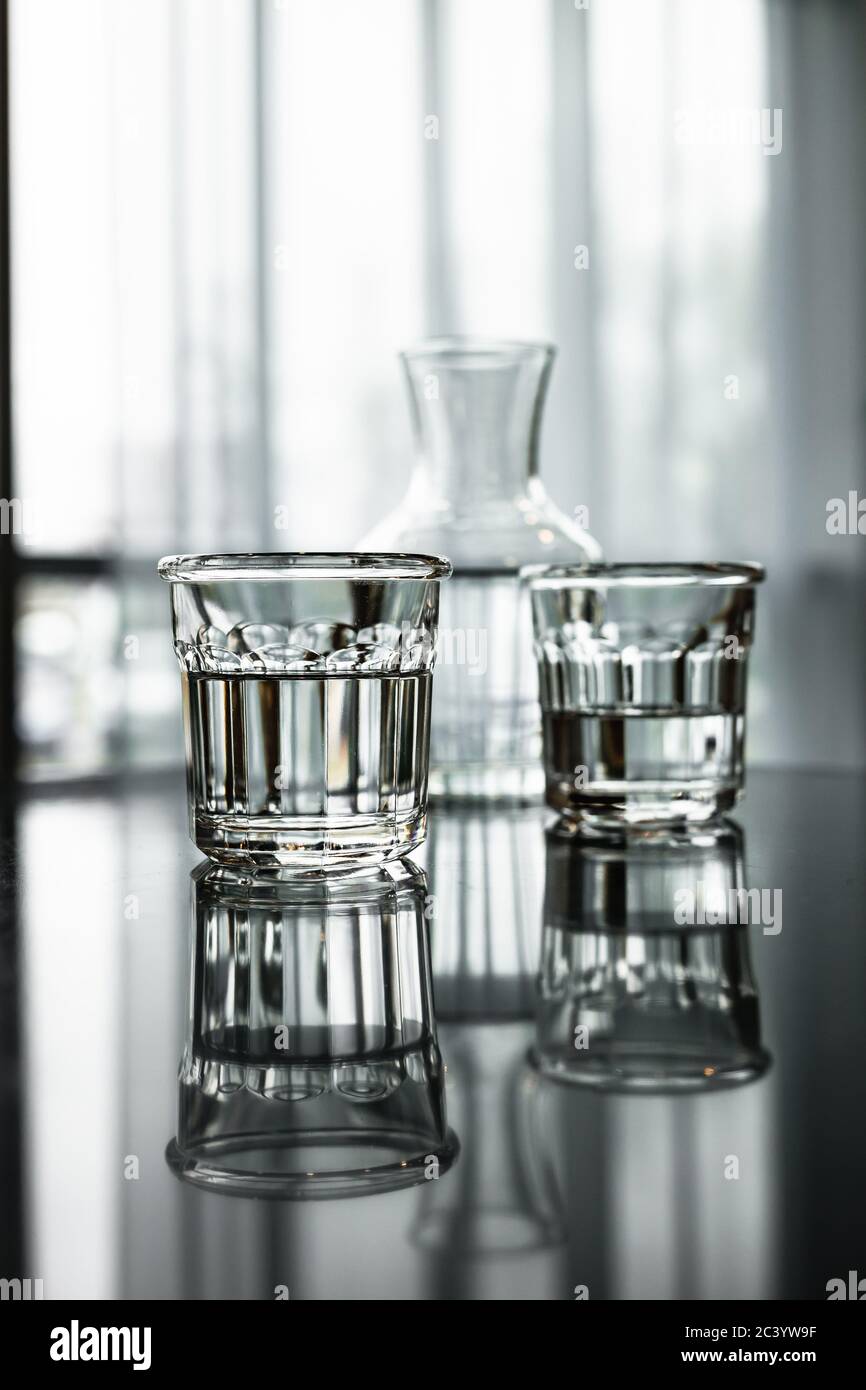 Deux verres d'eau et une carafe, reflectioning dans une table noire. Image verticale. Banque D'Images