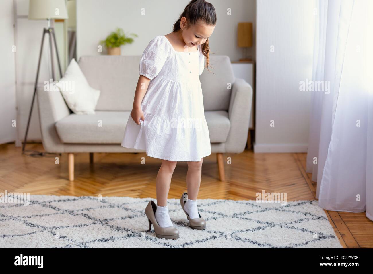 Petite fille portant des chaussures à talons hauts pour maman jouant à la  maison Photo Stock - Alamy