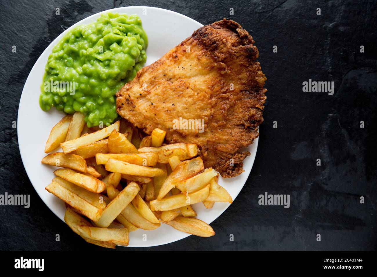 Une portion de poisson et de frites maison avec des petits pois. Le poisson est une aile frite et battue d'un rayon de thorignback, Raja clavata, et les frites sont Banque D'Images