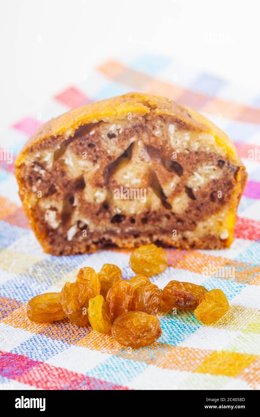 Close up low angle shot d'un muffin à moitié mangé et un grand groupe de raisins sur un chiffon de tissu avec un fond blanc. Banque D'Images