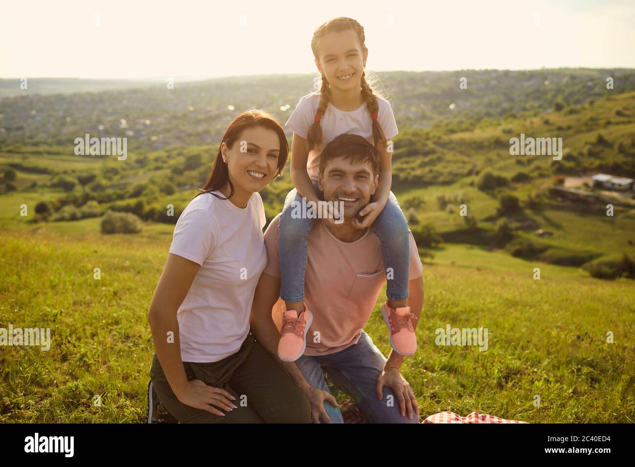 Une famille heureuse passe du temps ensemble dans la nature au coucher du soleil. Portrait de la jolie fille et de ses parents en vacances d'été Banque D'Images