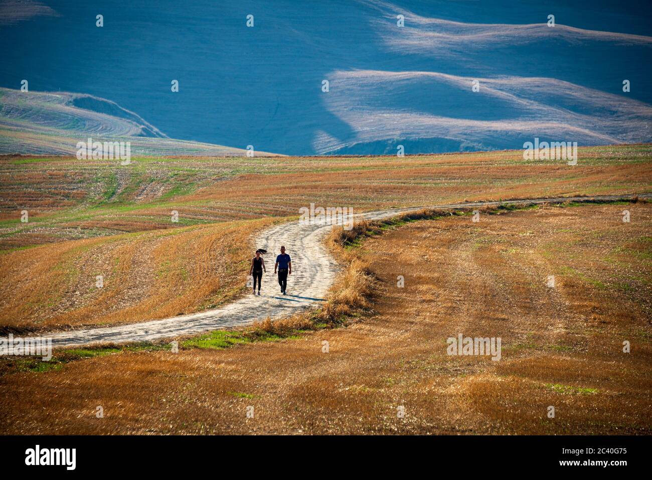 Deux randonneurs se balader un dimanche matin dans la campagne lumineuse de la crète senesi à proximité d'Asciano Banque D'Images