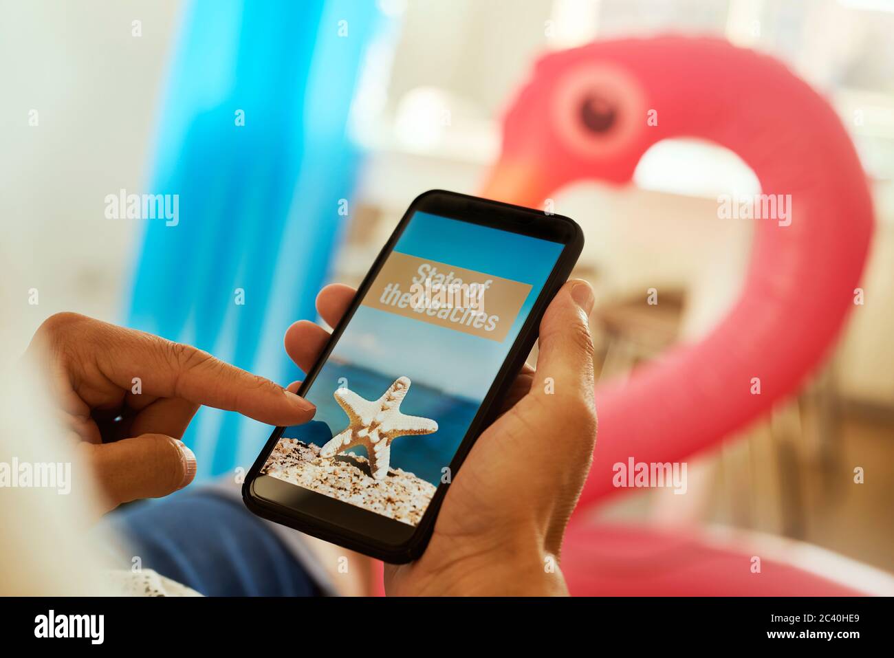 jeune homme, portant des vêtements d'été décontractés, assis sur un fauteuil, ayant son smartphone entre ses mains avec le texte état des plages dans son écran, Banque D'Images