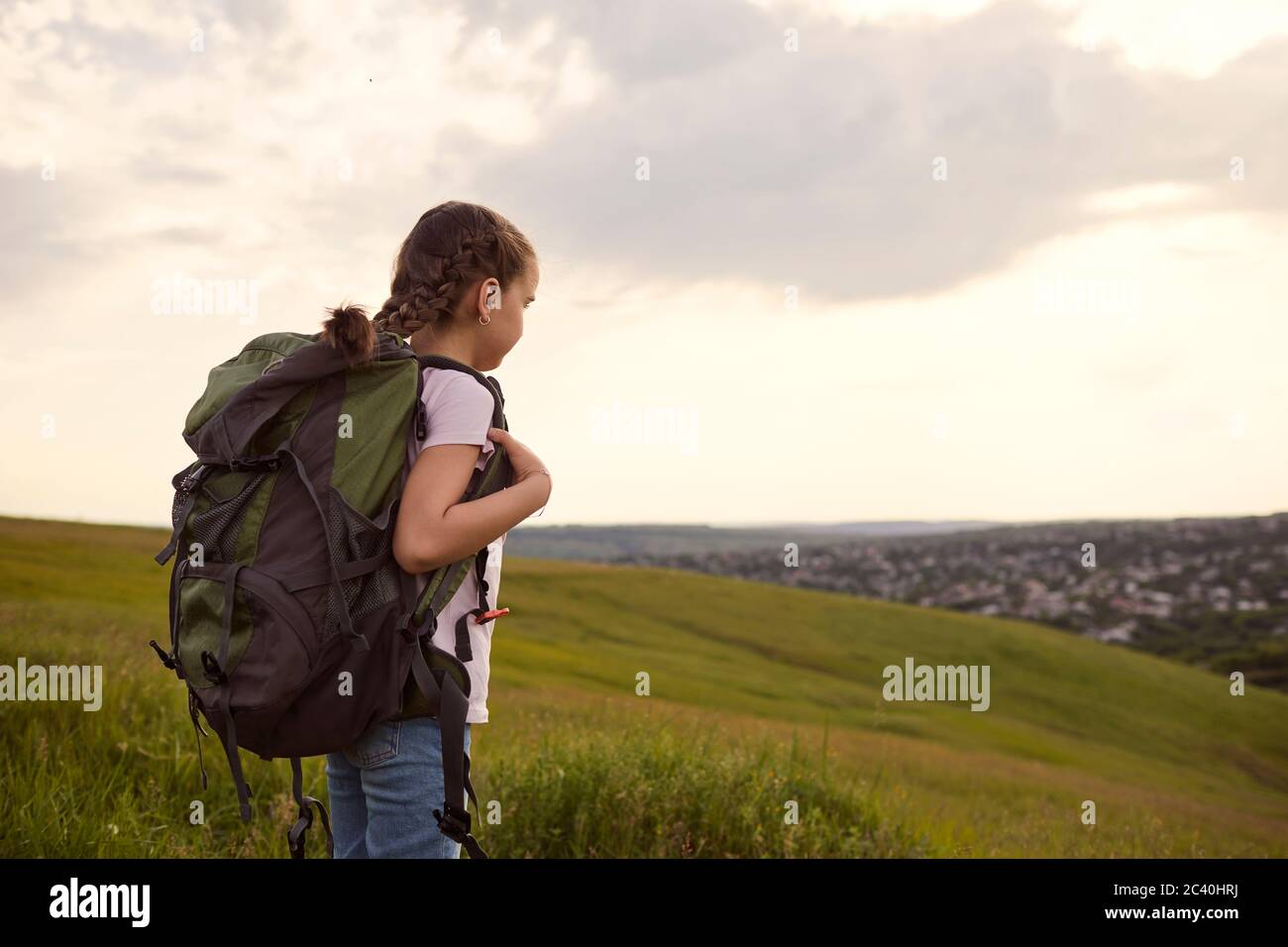 Petite fille touristique avec un sac à dos sur une randonnée marche avant dans la nature vue arrière. Banque D'Images