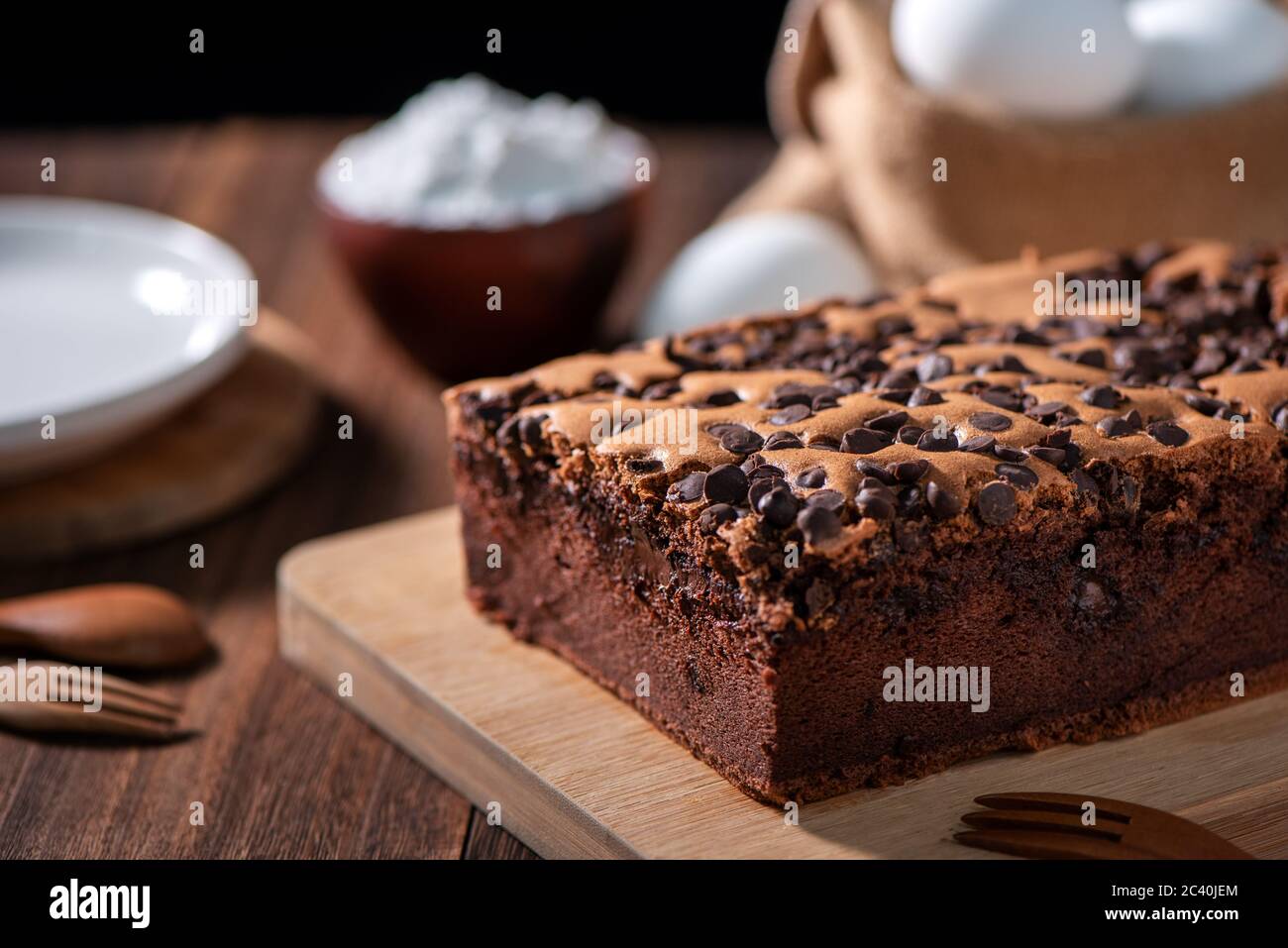 Gâteau éponge traditionnel taïwanais au goût de chocolat (taïwanais castella kasutera) sur une table de fond en plateau de bois avec les ingrédients, gros plan. Banque D'Images