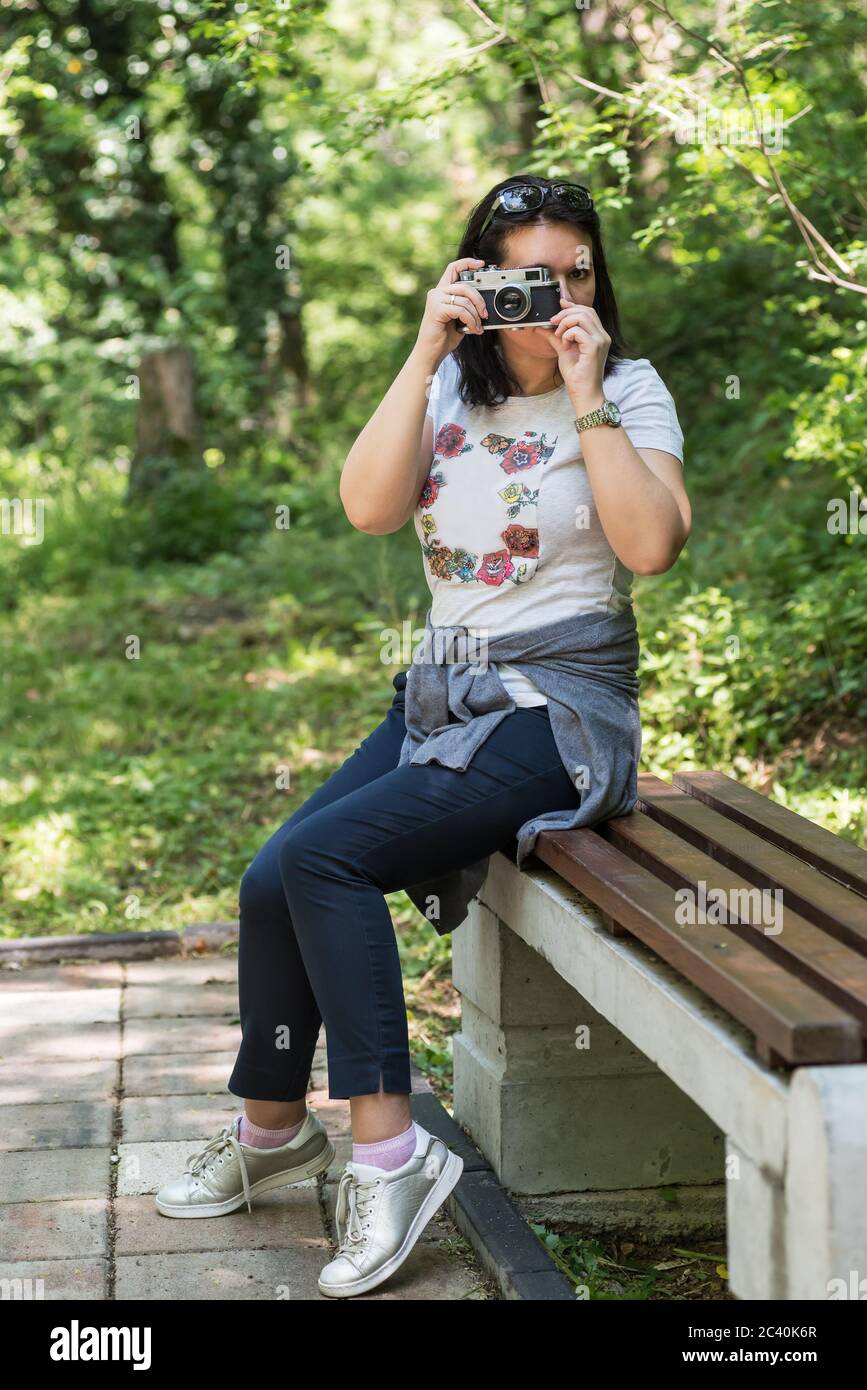 Femme prenant des photos dans un parc extérieur avec un espace de copie. Belle femme photographe touristique avec appareil photo vintage. lady photographe, femme Portrait. Banque D'Images