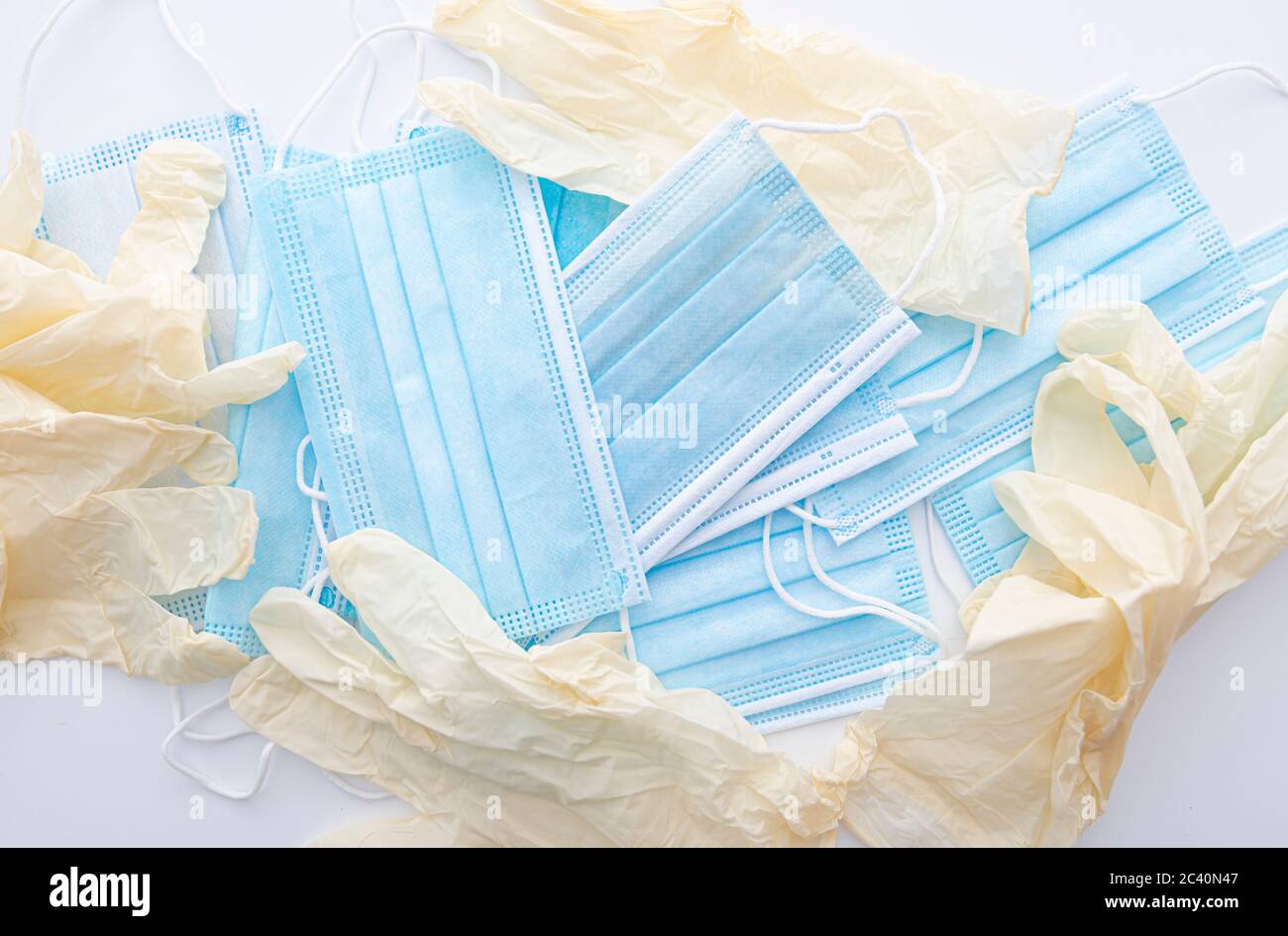 Tas de masques médicaux et de gants médicaux sur table blanche à l'hôpital, image conceptuelle Banque D'Images