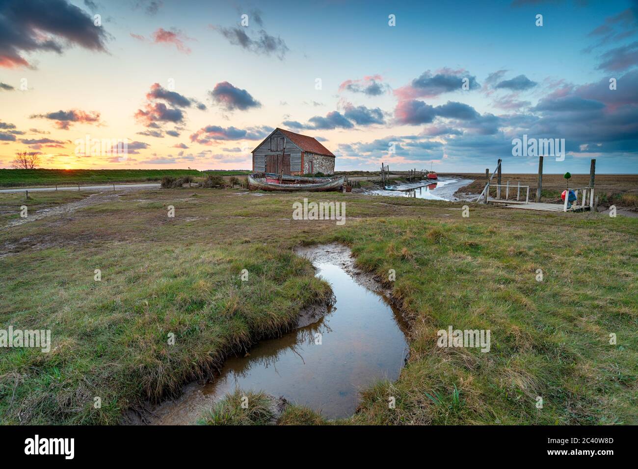 Coucher de soleil sur l'ancienne grange à charbon de Thornham, sur la côte nord de Norfolk Banque D'Images Coucher de soleil sur l'ancienne grange à charbon de Thornham, sur la côte nord de Norfolk Banque D'Images