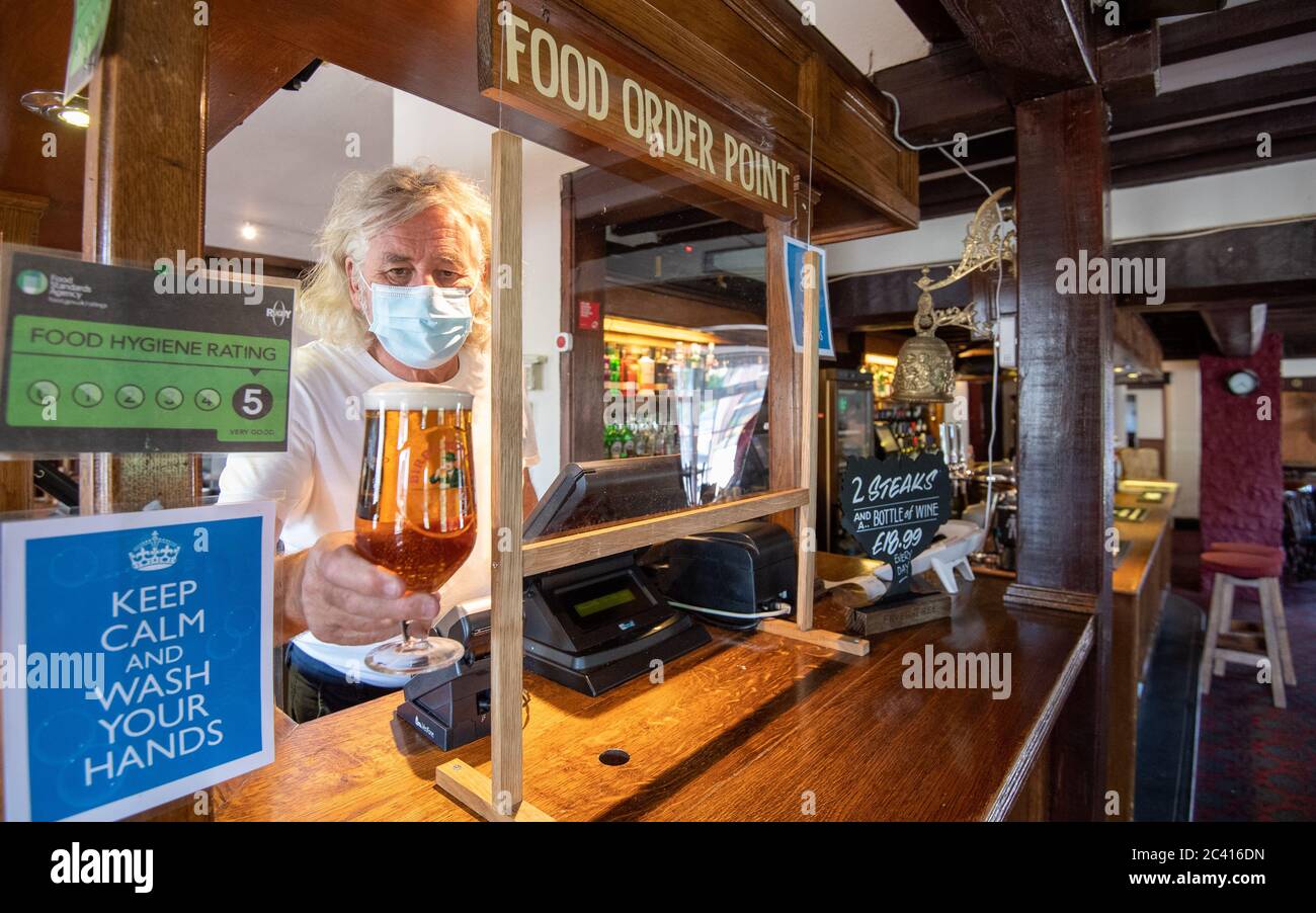 Phil Weaver, propriétaire du pub Old Smithy à Church Lawford, Warwickshire, détient une pinte de bière derrière un écran protecteur, tandis que les patrons de pub et d'hospitalité ont applaudi les propositions du gouvernement de permettre à leurs clients de passer leurs portes le 4 juillet comme un « soulagement bienvenu ». Banque D'Images