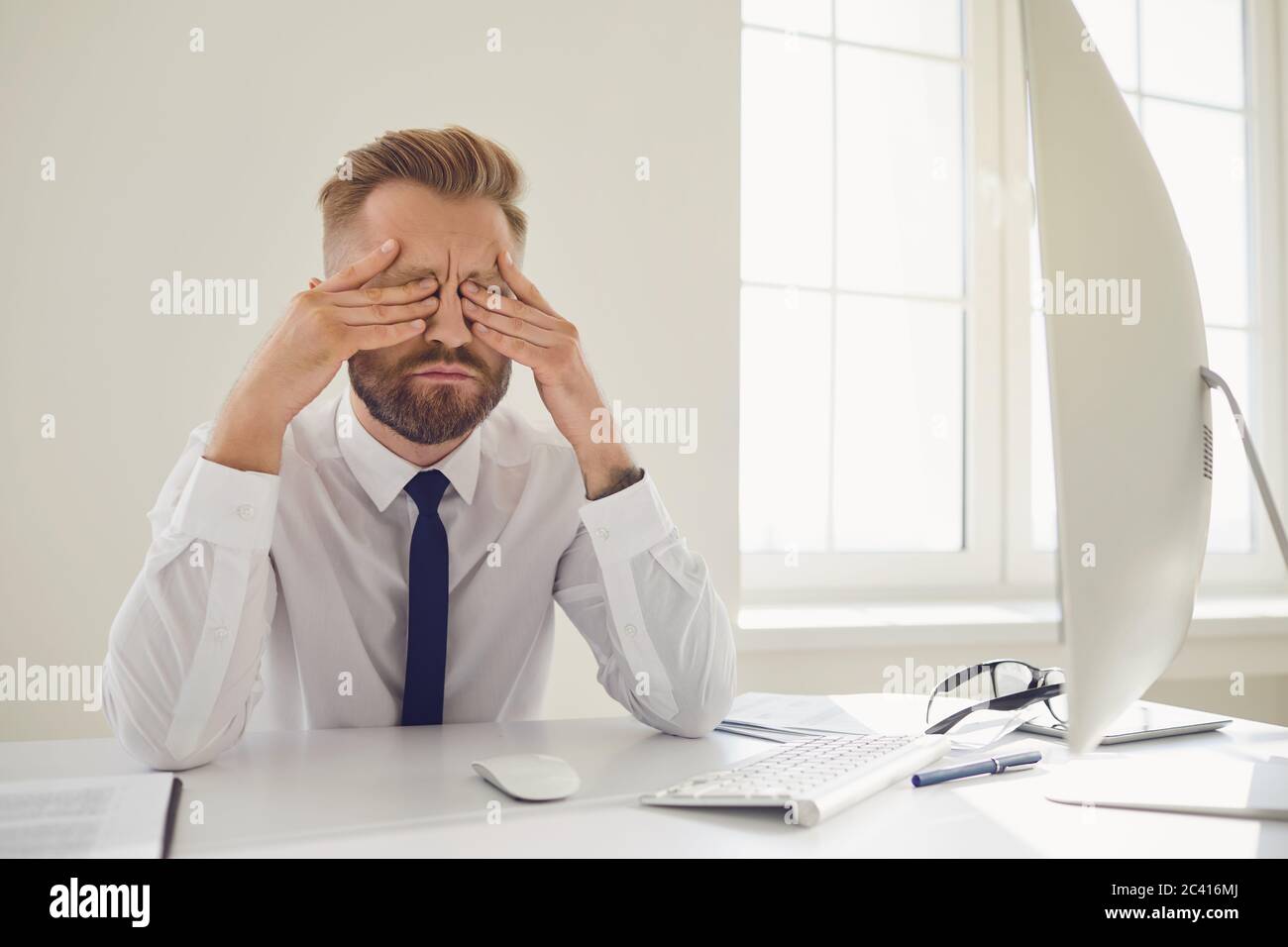 Un homme d'affaires très occupé lit les documents de travail assis à une table avec un ordinateur au bureau. Banque D'Images