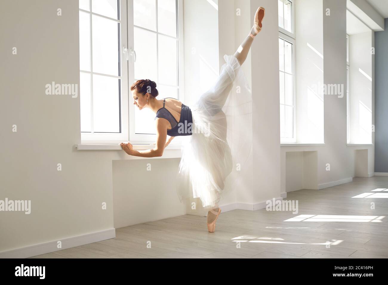 Ballerine. Une jeune danseuse de ballet gracieuse répète une représentation dans un studio de classe blanche Banque D'Images