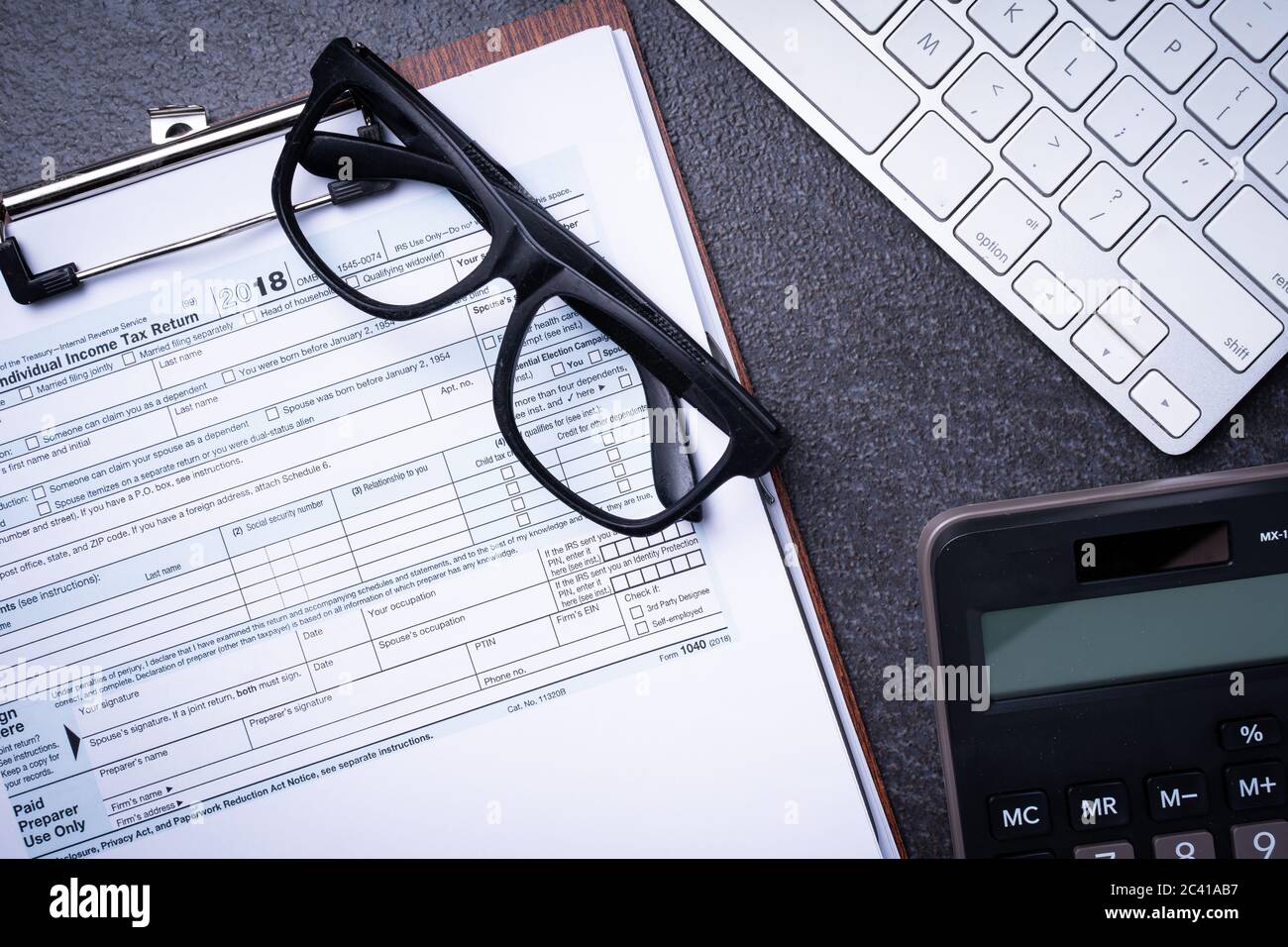 Formulaire de remboursement de l'impôt sur le revenu sur un bureau avec pièces et calculatrice Banque D'Images