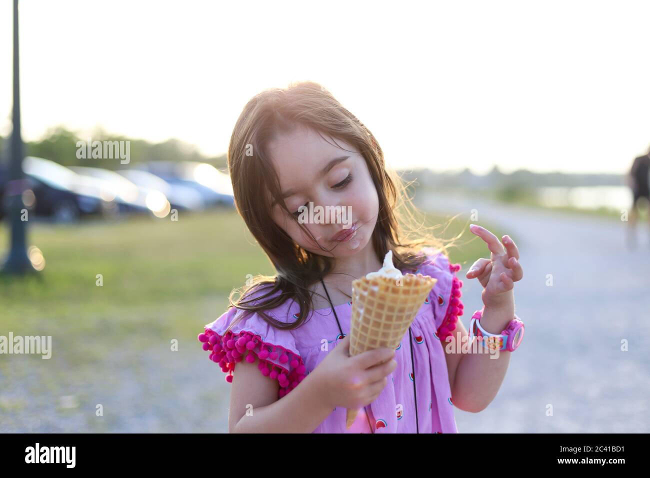 Une petite fille dans une robe rose tenant un grand cône gaufré Banque D'Images