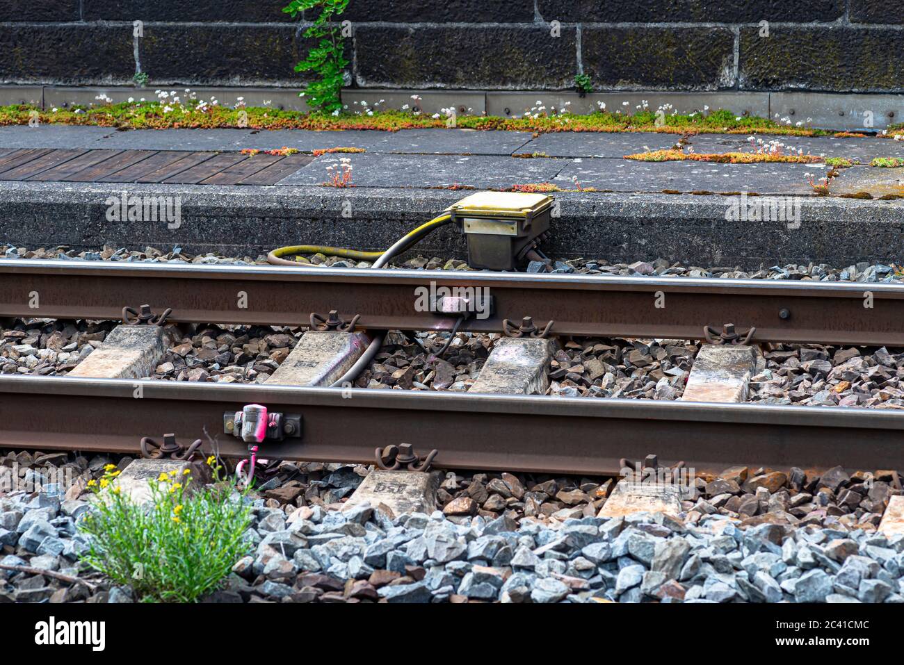 Voies ferrées reposant sur des traverses en béton, remplissant de grandes pièces de roche, système visible sur l'unité de détection de compteur d'essieu et la chaussée. Banque D'Images
