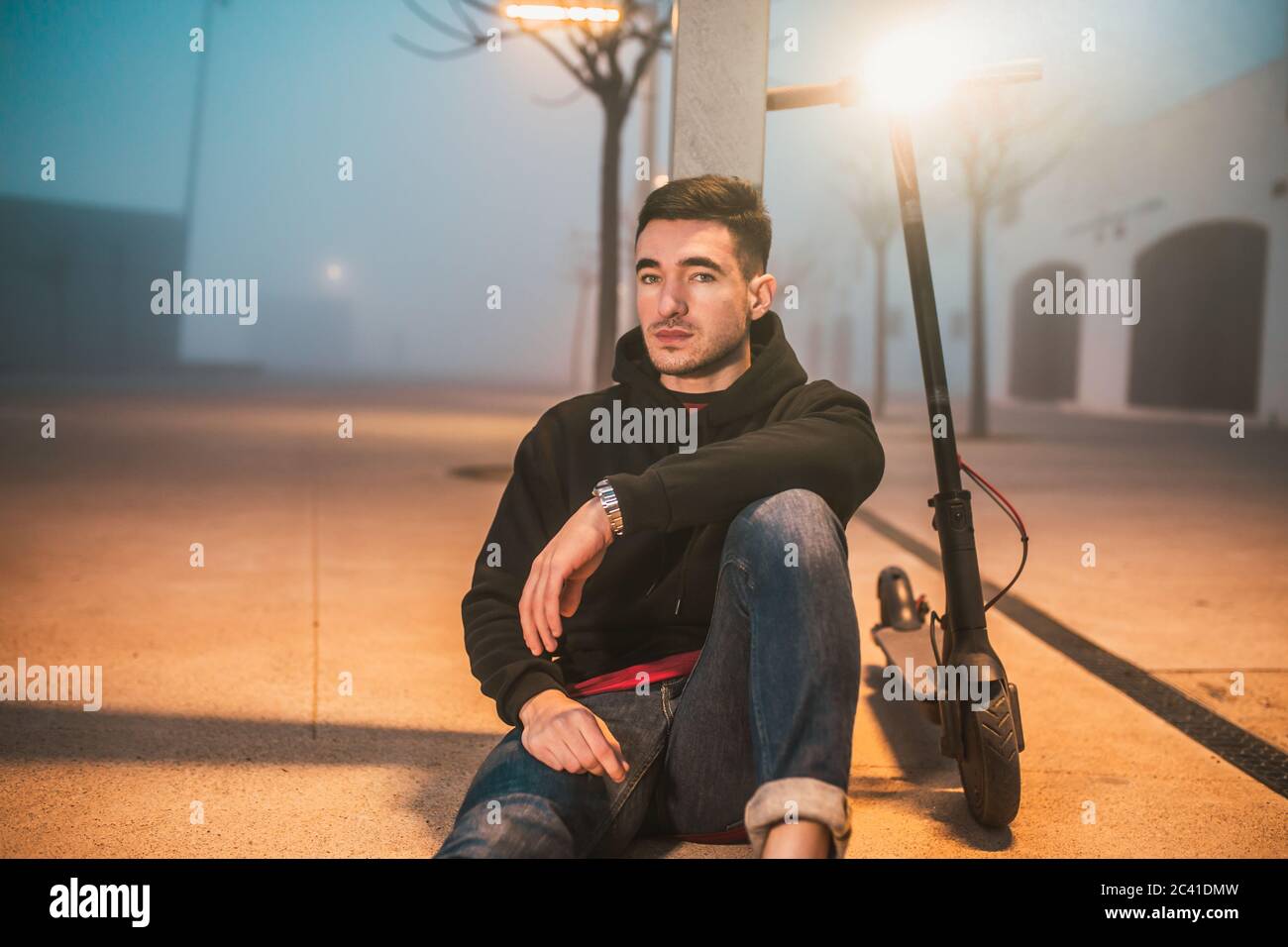 homme assis à côté de son scooter électrique, il regarde la caméra Banque D'Images