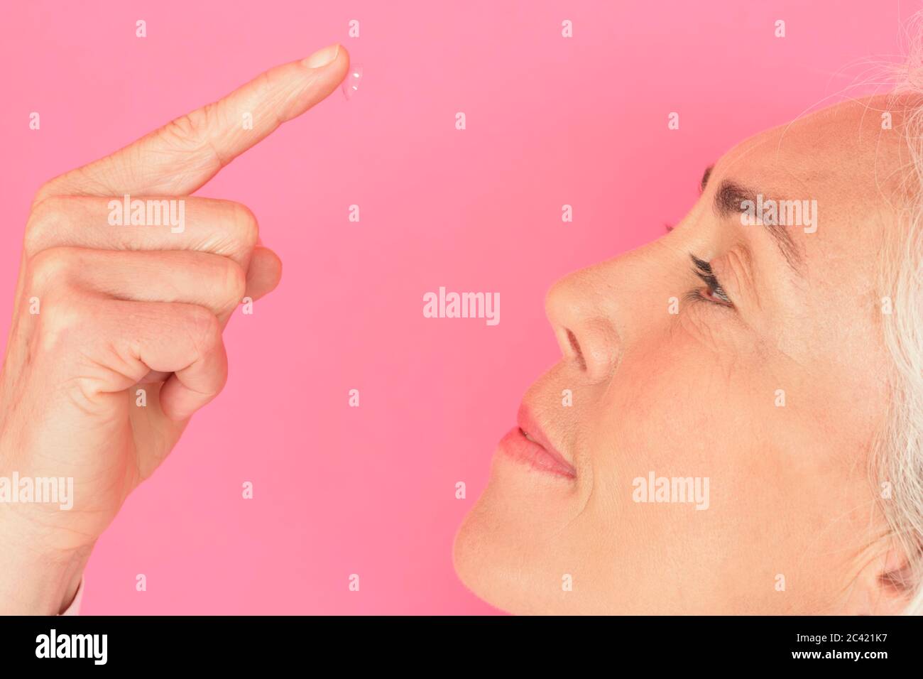 Une femme âgée veut utiliser une lentille de contact Banque D'Images