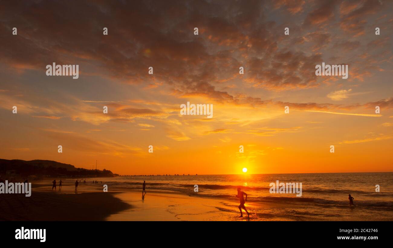 Les touristes marchant sur la plage au coucher du soleil brillent dans la mer Banque D'Images