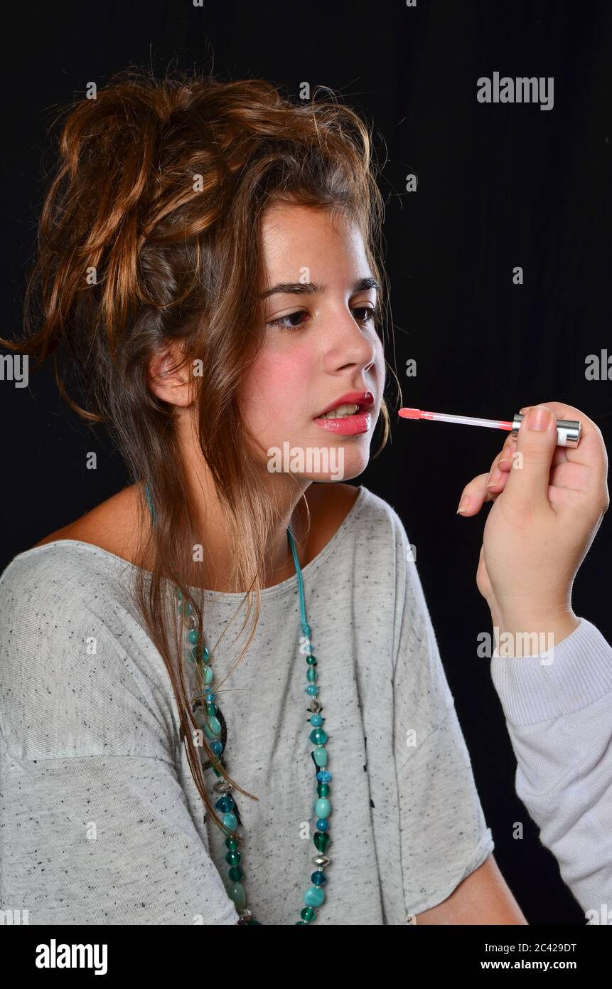 Maquillage professionnel de la jeune fille brune pendant la préparation de la séance de photo, studio tourné sur fond noir Banque D'Images