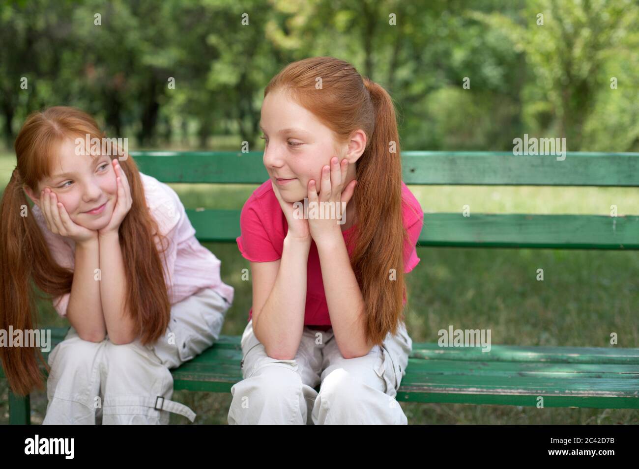 Jumeaux sur un banc de parc, contact visuel Banque D'Images