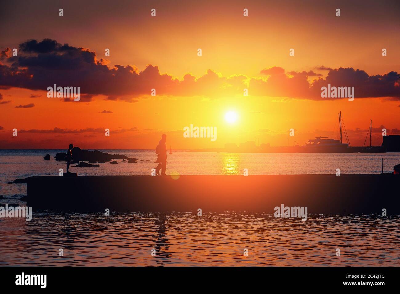 Coucher de soleil spectaculaire sur la mer méditerranée et silhouette de jetée avec des touristes méconnus, ambiance romantique. Banque D'Images