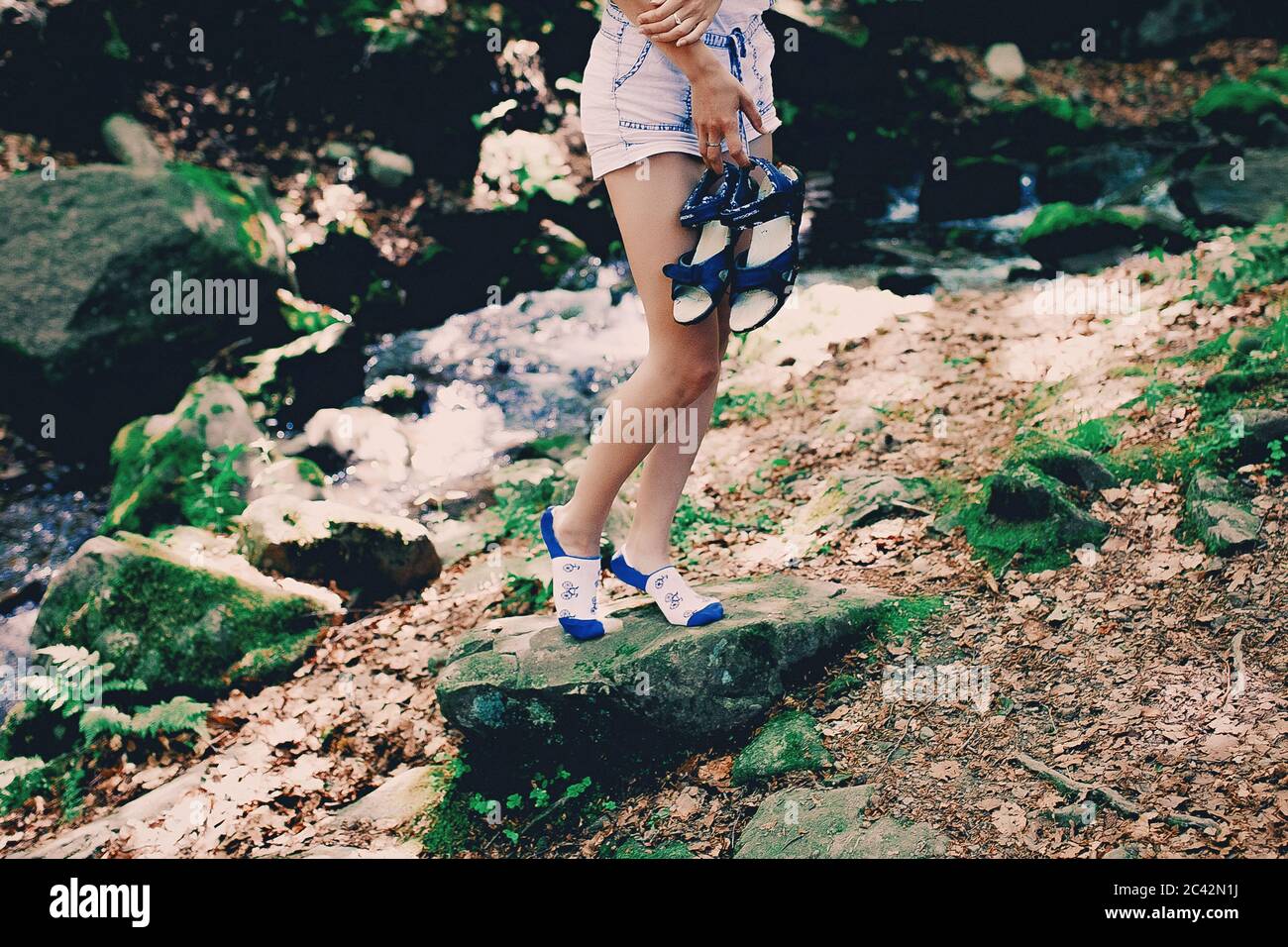 Jeune fille de hipster assis sur un rocher à la rivière dans la forêt en chaussettes lumineuses imprimées à la cascade de Shipit, cascade dans les Pylypets dans la forêt. Carpalien Banque D'Images
