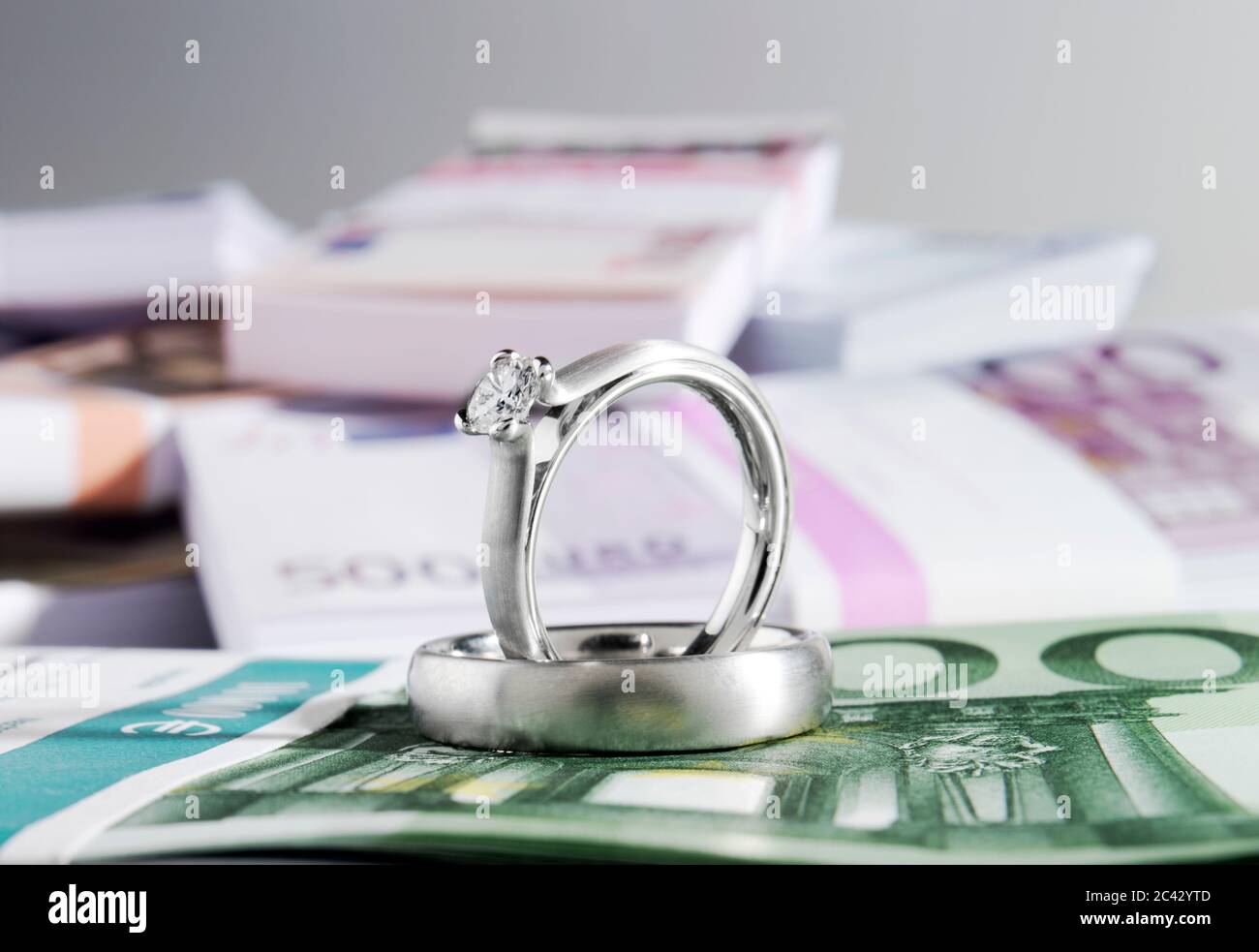 Deux anneaux de mariage et une pile de billets Banque D'Images
