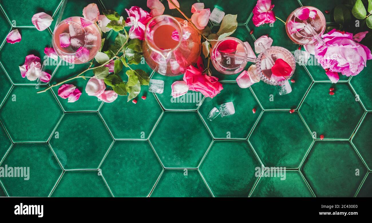 Boisson fraîche rafraîchissante en été. Lit de limonade à la rose avec glace en verre et pétales de fleurs roses sur fond de table en carreaux verts, vue du dessus Banque D'Images
