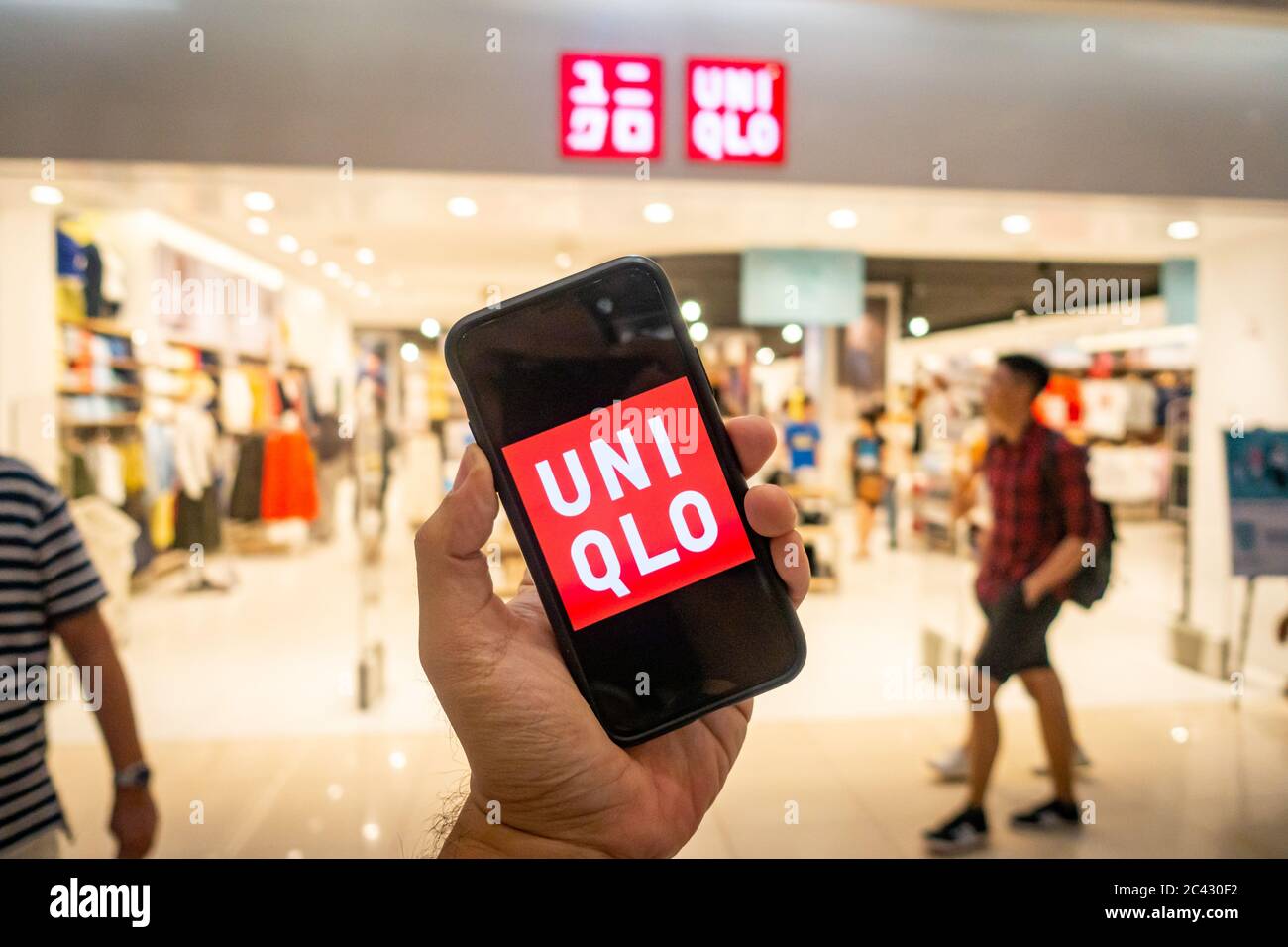 Main d un homme tenant un iphone X avec des applications uniqlo en face du magasin Uniqlo. Uniqlo apps est parfait pour ceux qui preferent le shopping en ligne Photo Stock Alamy