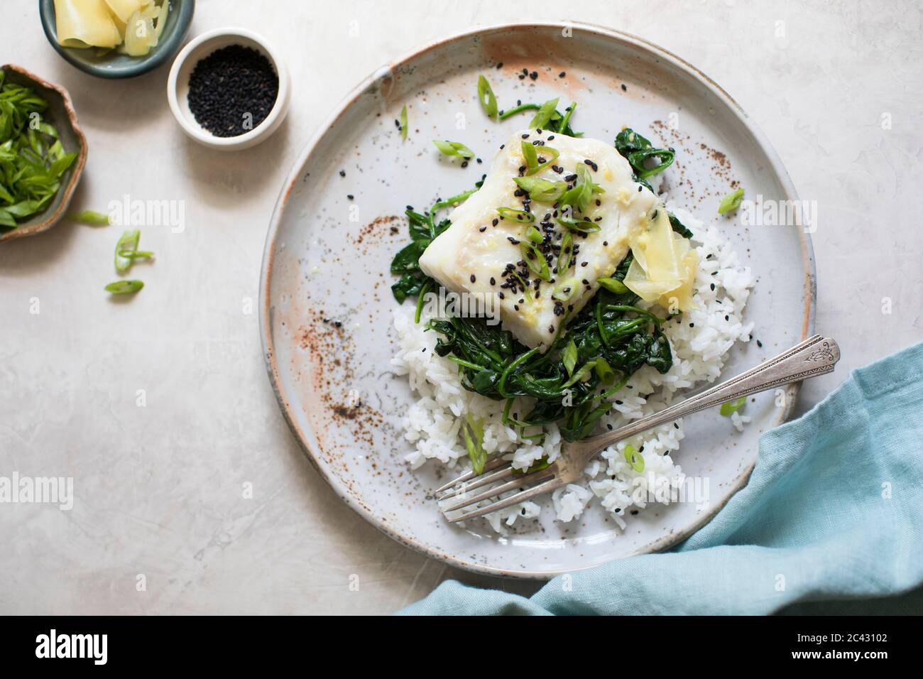 Filet de poisson blanc cuit, épinards flétris et haricots verts sur un lit de riz. Banque D'Images