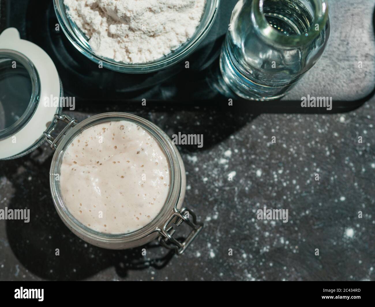 Démarreur de levain de blé. Bol en verre avec entrée de levain sur fond sombre, espace de copie. Banque D'Images