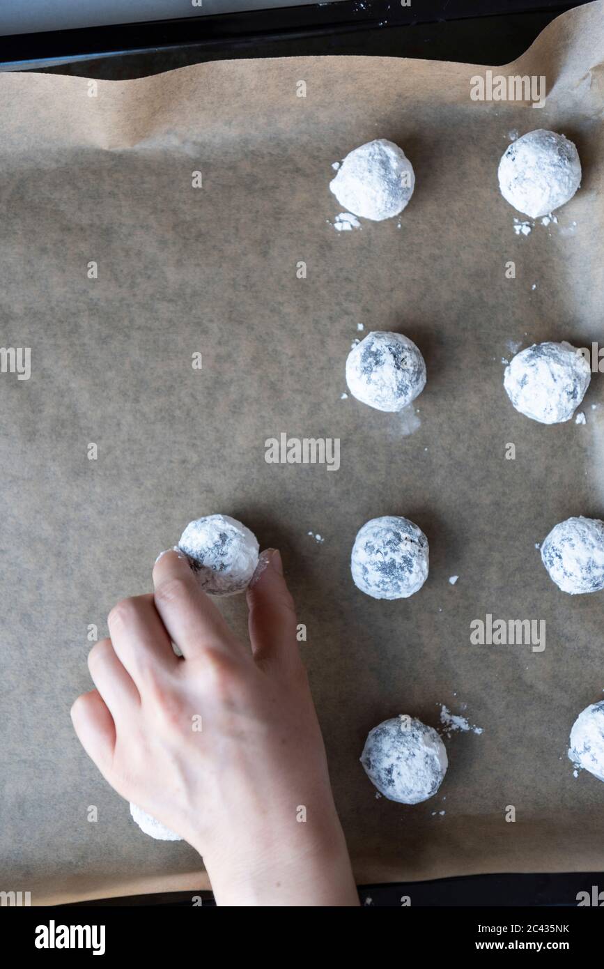 Placer des petits pains de chocolat enrobés de sucre en poudre sur une plaque à pâtisserie. Banque D'Images
