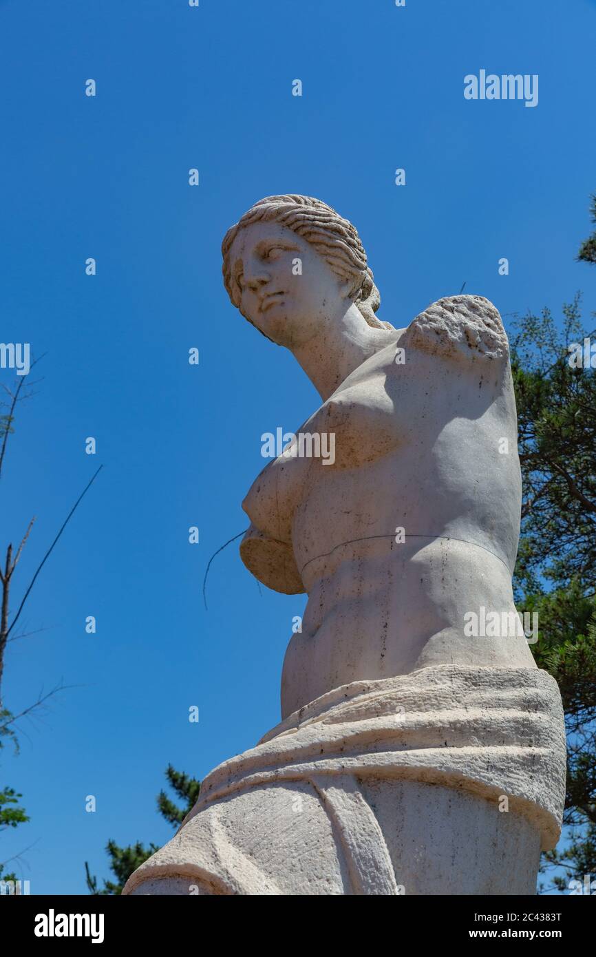 Arbre extérieur bleu ciel vert, statue de Vénus de bras cassé, mythologie romaine, Aphrodite Banque D'Images